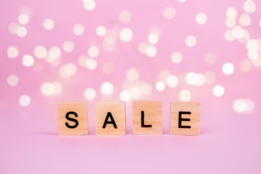 Words Sale on a blurred pink background with beautiful bokeh garland lights. With copyspace Concept of holidays christmas, valentine's day, black friday, mothers day and seasonal discounts