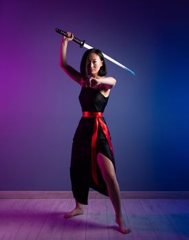 the slender Asian woman in a black dress with a katana in her hand image of a samurai on a neon background