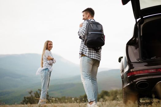 Young couple on road trip relaxing and enjoying the view of mountains