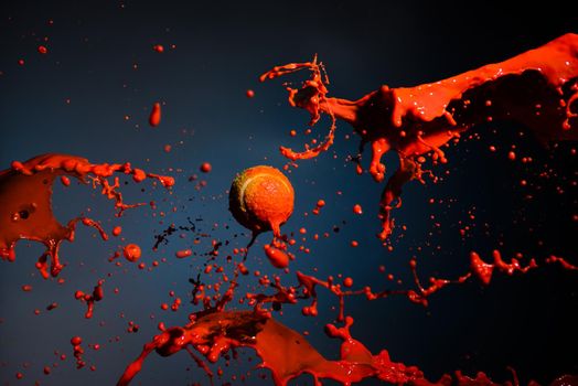 red paint splash and tennis ball on blue background.