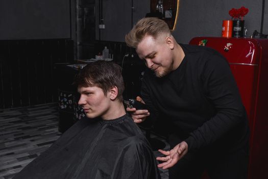 Barber European looking man hairdresser cuts the client with dark hair. Hairdressing.
