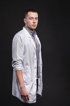 Portrait of a young intern doctor. A man is standing in a photo studio. Making a diagnosis. Studio portrait.
