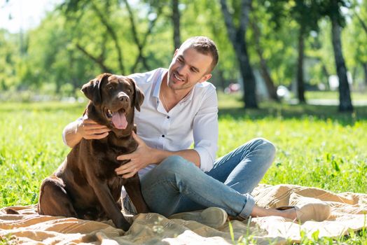 Young man hugs a dog. Spending time with friends in the park