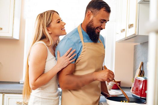 Young loving couple cooking together in kitchen at home