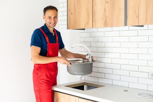 partial view of repairman in working overall fixing sink in kitchen