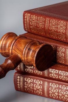 Brown wooden gavel with stack of books on gray table. Close up.