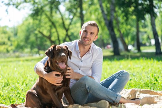 Young man hugs a dog. Spending time with friends in the park