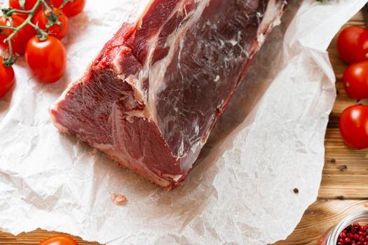 Raw T-bone steak with herbs on wooden board, close up