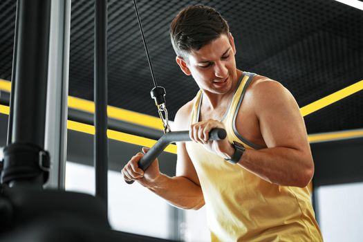 Young bodybuilder doing heavy weight exercise for biceps in a gym, close up