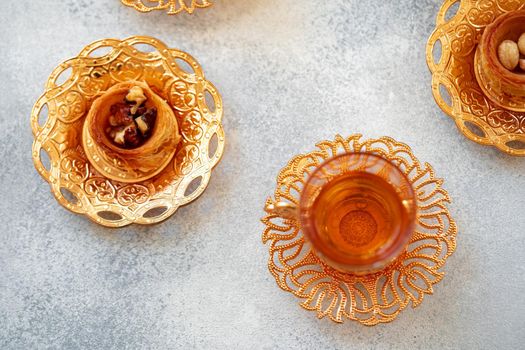 Turkish baklava and Turkish tea in oriental dishes on gray background, close up