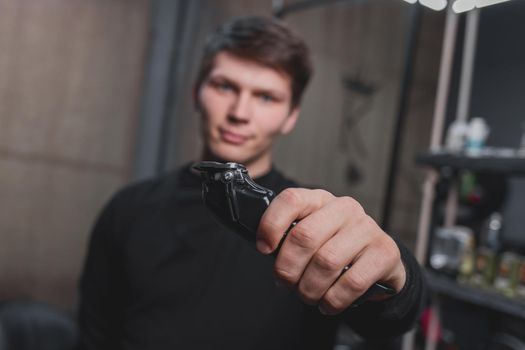 A guy holds an electric shaving machine. Hairdressing.