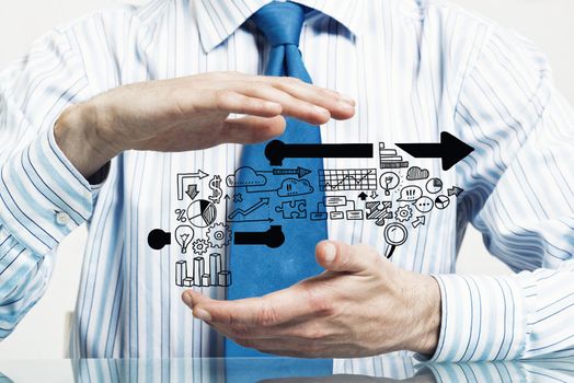 Businessman in suit sitting at desk making protective gesture with palms