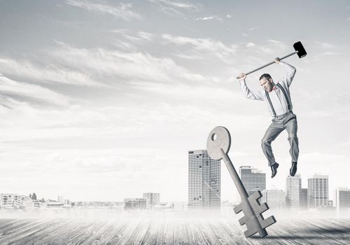 Determined businessman against cityscape breaking with hammer stone key figure