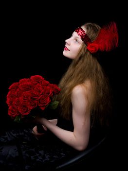 A beautiful teenage school girl is photographed in the studio with a large bouquet of flowers, against a black background.