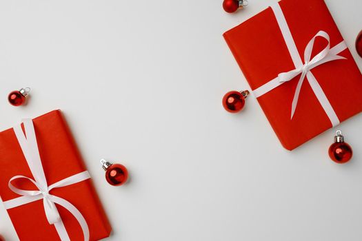 Red gift boxes and Christmas baubles on white background top view