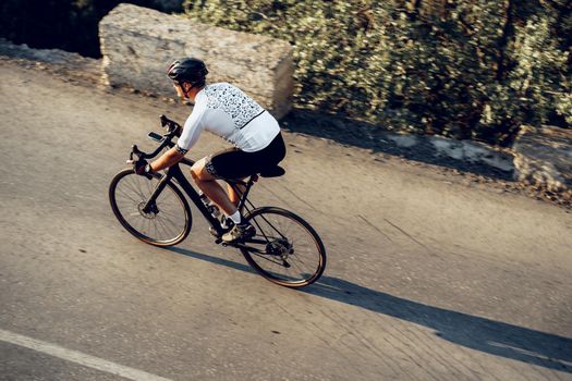Professional man cyclist on a mountain road at sunrise