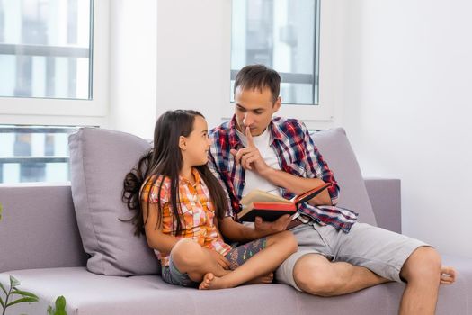 a young father with his little daughter reads the Bible