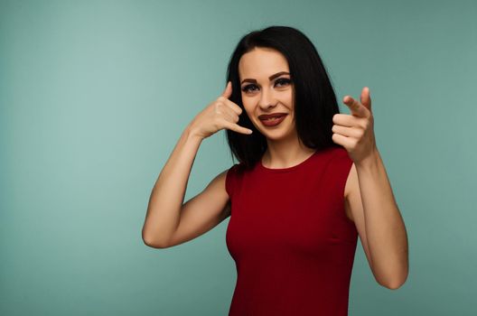 Portrait of an young woman looking and pointing at you saying call me on isolated background - Image
