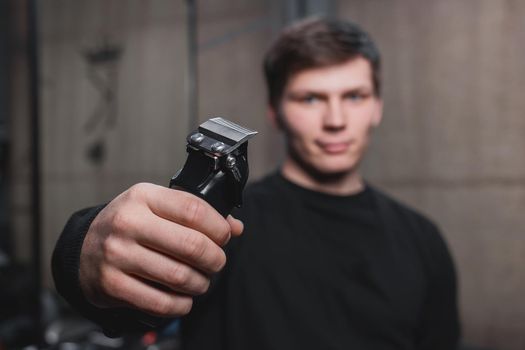 A guy holds an electric shaving machine. Hairdressing.