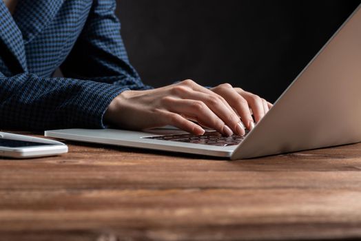 Close up woman hands lying on laptop keyboard. Business lady working with computer at wooden desk. Financial specialist working at workplace in office. Business accounting and project management.
