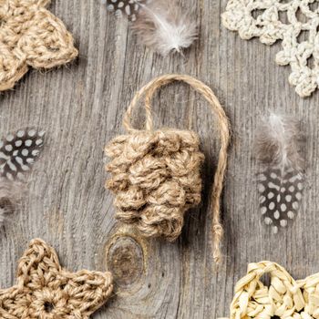Winter or Christmas wooden background with jute crochet pine cone ornament. Handmade Christmas decorations made of natural materials. Top view