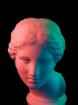 Gypsum copy of ancient statue of Venus de Milo head for artists isolated on a black background. Plaster sculpture of woman face. Multi color toned.
