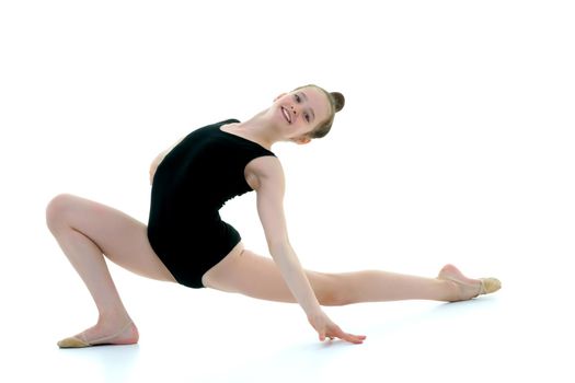 A sweet little gymnast girl performs an acrobatic element on the floor. The concept of sport, healthy lifestyle. Isolated on white background.