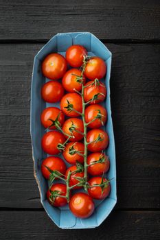 Fresh red organic cherry tomatoes, on black wooden table