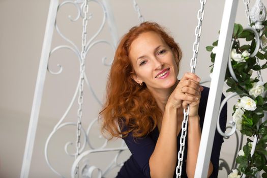 Beautiful young woman posing in the studio on a swing. Style and fashion concept.