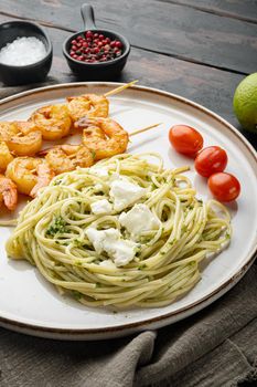 Italian pasta spaghetti with grilled shrimps, pesto sauce set, on plate, on old dark wooden table background