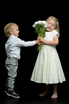 A little boy gives a girl a bouquet of flowers for his birthday. The concept of love, family values. Isolated