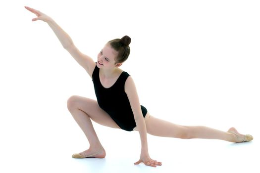 A sweet little gymnast girl performs an acrobatic element on the floor. The concept of sport, healthy lifestyle. Isolated on white background.