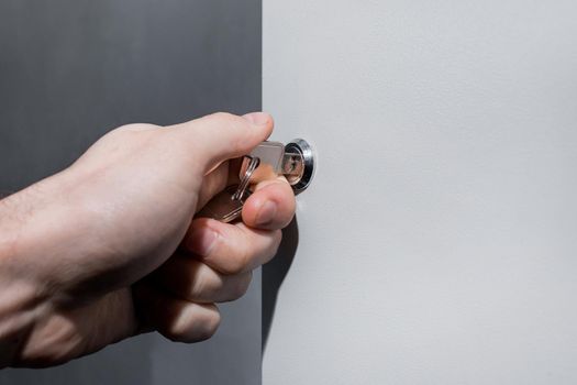 The hand of a human electrician opens or closes the electrical box with a metal key. Safe technologies and control system of electrical equipment.