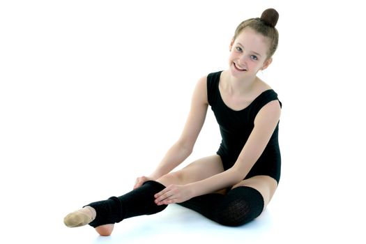 Girl gymnast puts on her leg black leggings. Sport concept, isolated on white background.