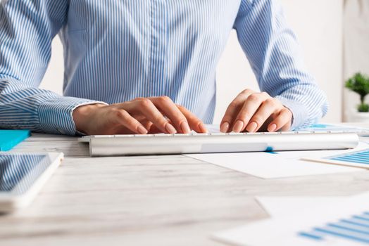Manager typing on computer keyboard at wooden desk. Strategy planning and banking. Financial analyst working in office. Business accounting and project management. Close up woman hands on keyboard