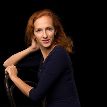 Fashion, artistic portrait of a beautiful red-haired model girl, with long hair on a black background.