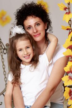 Mother and daughter swinging on vintage baby swing. Close-up