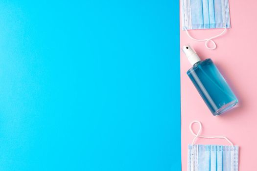 Medical face mask on pink and blue paper background with copy space top view