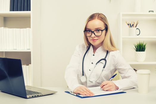 Young beautiful doctor woman working happy and smile in hospital, sitting on table, medical concept, toned