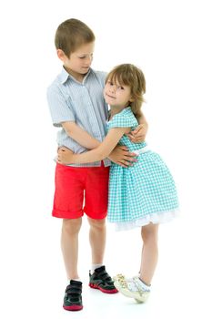 Charming little girl hugging a tall boy with blond hair. A romantic couple is happy with the joint time brought. A happy sister hugs her brother. The concept is a happy childhood. Isolated on white background.