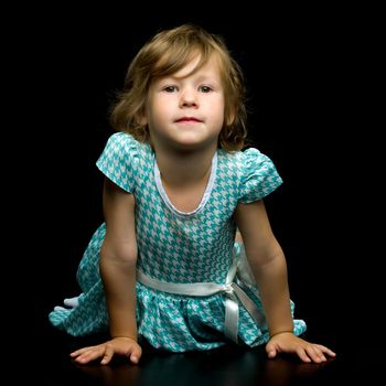 Charming little girl is lying on the studio floor on a black background. Concept for happy childhood, style and fashion