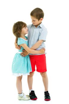 Charming little girl hugging a tall boy with blond hair. A romantic couple is happy with the joint time brought. A happy sister hugs her brother. The concept is a happy childhood. Isolated on white background.