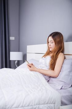 woman using her smartphone on bed in the bedroom