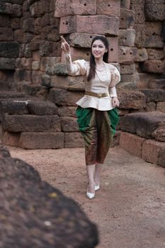 happy beautiful woman inThai traditional dress is pointing