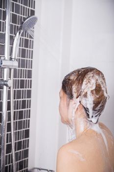 woman washing her head and hair in the shower by shampoo