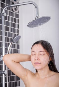 Woman is washing her hair and face by rain shower head