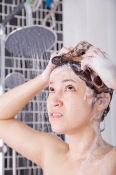 unhappy woman washing head with shampoo and the shower