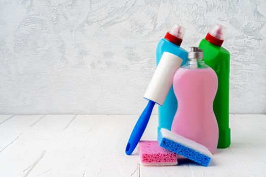 Household cleaning detergents on wooden table against gray background, close up