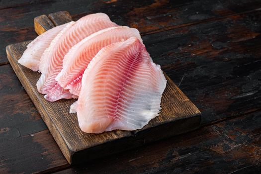 Tilapia fish, skinless meat, on old wooden table