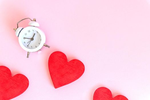 Time for love - Alarm clock and hearts on wooden and blue background